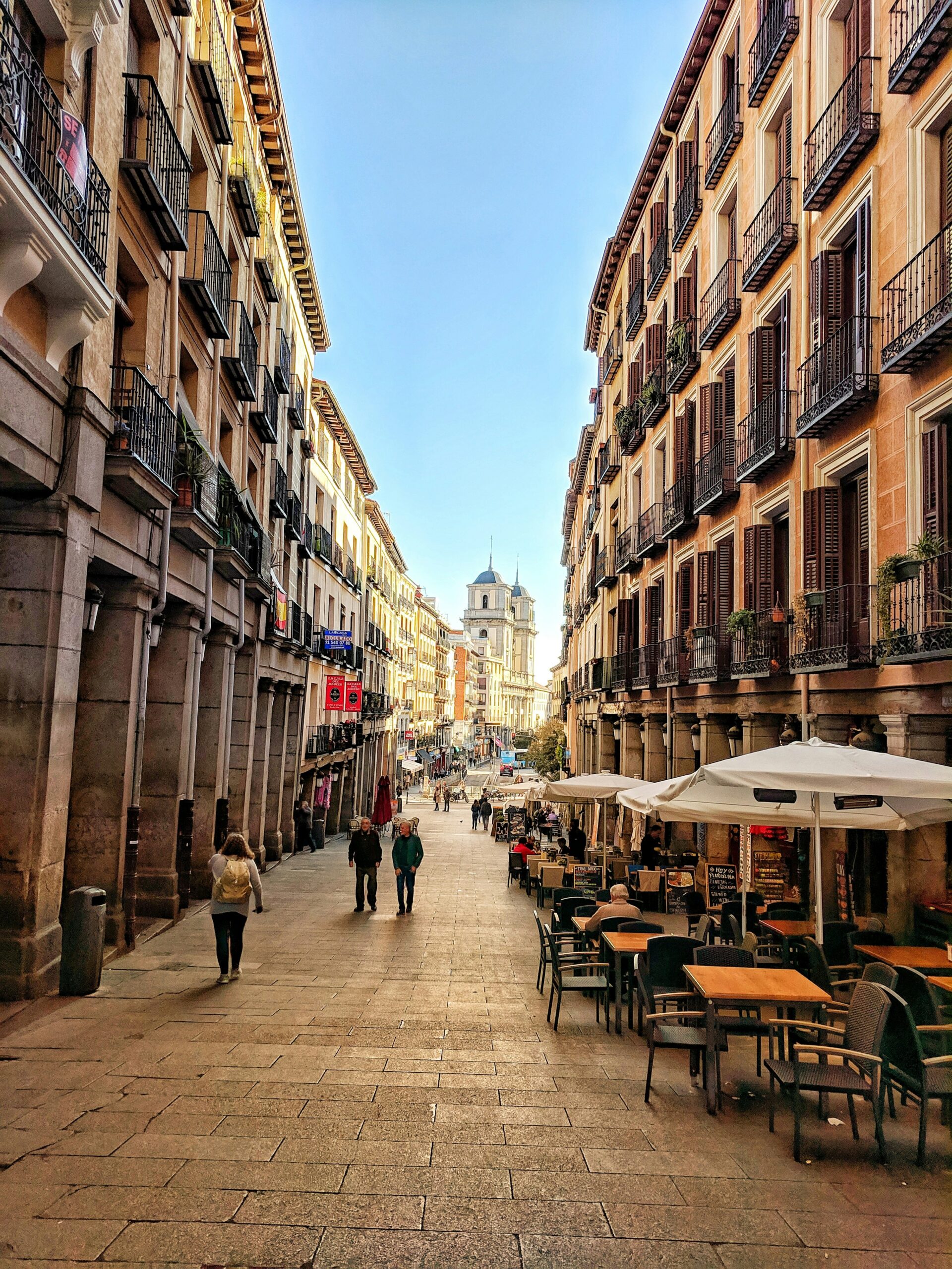 Leute laufen durch eine schmale Straße in der Nähe des Plaza Mayor.